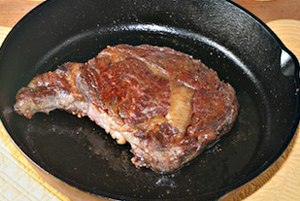 cooking rib eye steak in a cast  iron skillet
