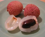 A plate of lychee showing a peeled fruit